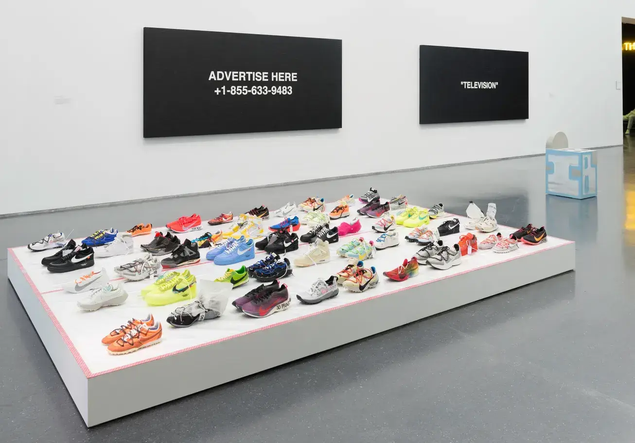 Archive image 4: An exhibition space featuring a large Nike swoosh and shoe illustration on a wall.
